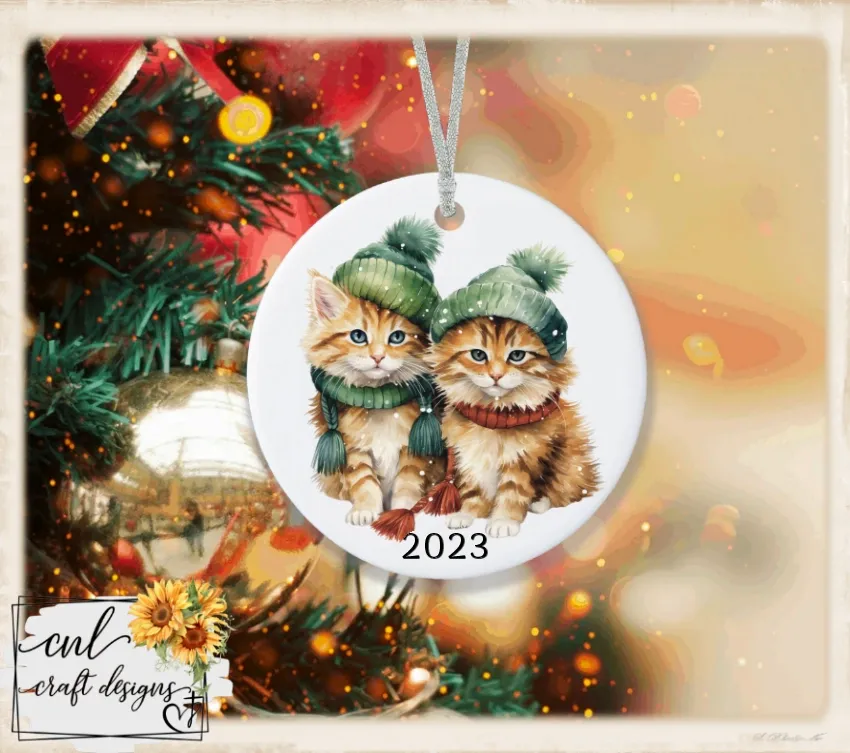 Ceramic ornament with two winter cats in knit hats, dated 2023